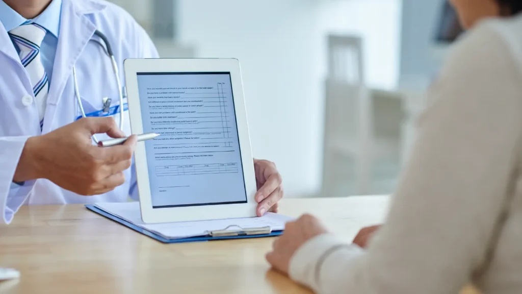 Medical professional points to tablet explaining clinical trial to participant